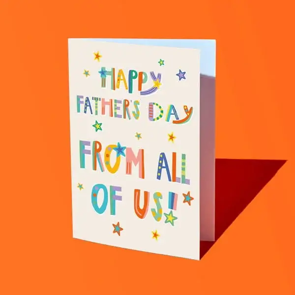 A colourful Fathers Day card reading Happy Father’s Day from all of us, decorated with playful lettering and star illustrations, displayed against a bright orange background.